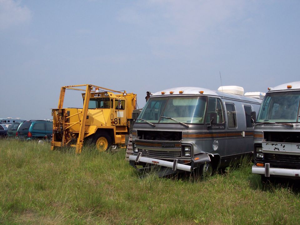 Gray motorhome with brown stripes, front view, parked in grassy lot