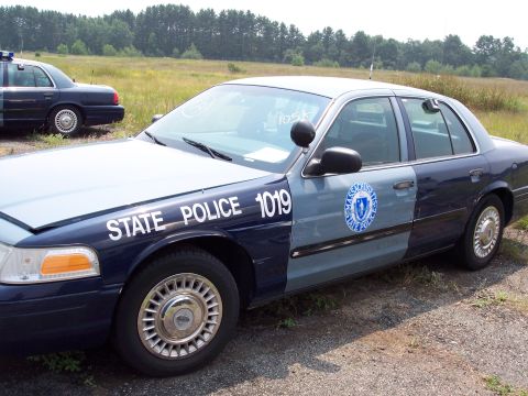 1991 Ford LTD Crown Victoria - Two Massachusetts State Police cars are parked in a grassy area. The closest car has 'STATE POLICE 1019' written on its side.