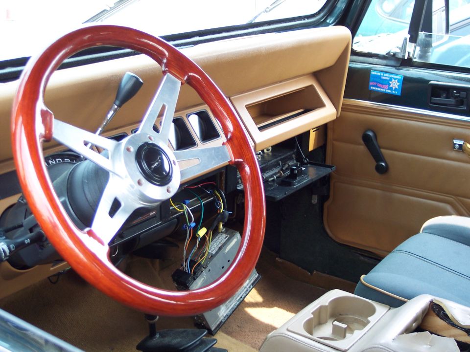 Aftermarket wood and chrome steering wheel in a Jeep's tan interior. Wires are visible under the dash