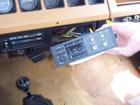 1991 Ford LTD Crown Victoria - A hand holds a Ford car radio, removed from the dashboard which shows vents and gauges.