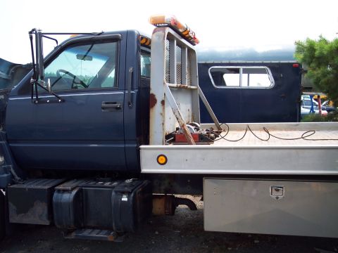 1991 Ford LTD Crown Victoria - This tow truck is seen from the side, a blue cab and a flatbed with amber warning lights.