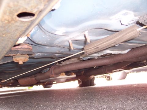 1991 Ford LTD Crown Victoria - The undercarriage of a vehicle, revealing the exhaust pipes and suspension components, with visible rust and questionable repairs.