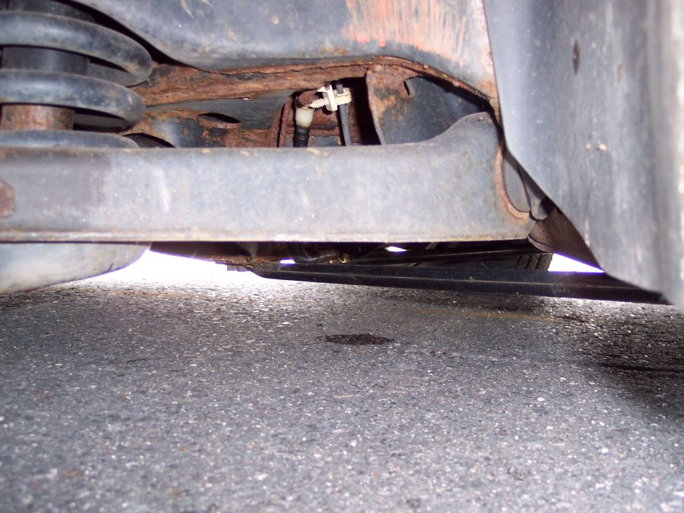 Close-up of rusted underbody and suspension components of a vehicle, viewed from below
