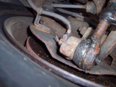 1991 Ford LTD Crown Victoria - This image shows heavily corroded suspension components, including a brake rotor and a greased ball joint.