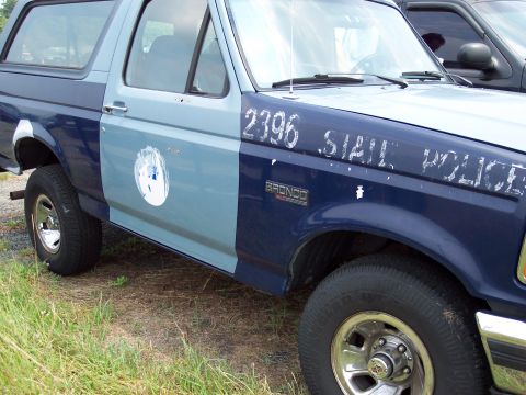 1991 Ford LTD Crown Victoria - A two-tone blue Ford Bronco police vehicle is parked next to another vehicle.