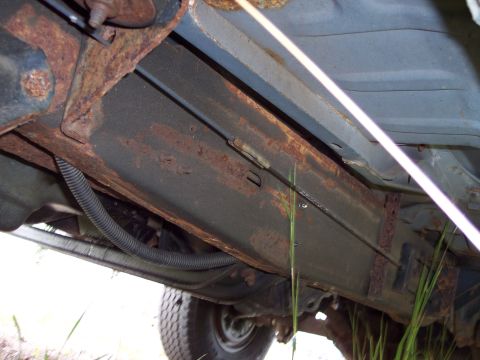 1991 Ford LTD Crown Victoria - Close-up of a heavily rusted vehicle frame, showing underbody components and a tire.