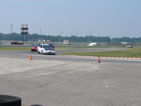 1992 Ford Taurus - Several cars are on a race track, with a white sedan in the foreground.