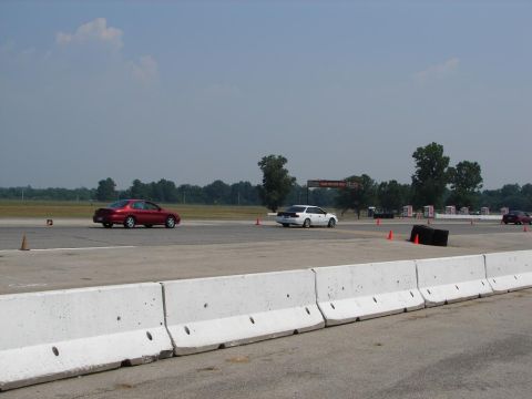 1992 Ford Taurus - A red sedan drives on a race track with other vehicles visible in the background.