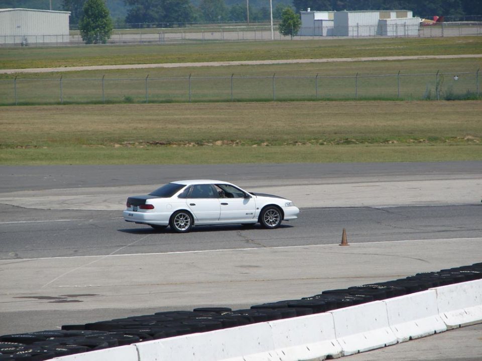 White 1992 Ford Taurus sedan with black hood and trunk on a race track