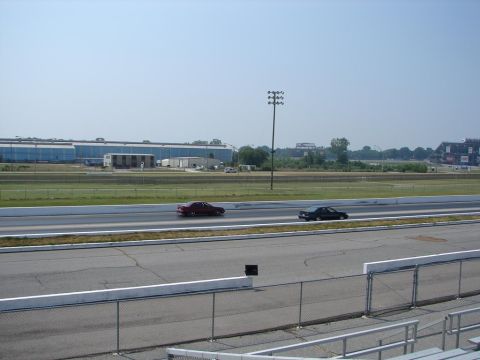 1992 Ford Taurus - Two cars compete on a drag strip under a clear sky.