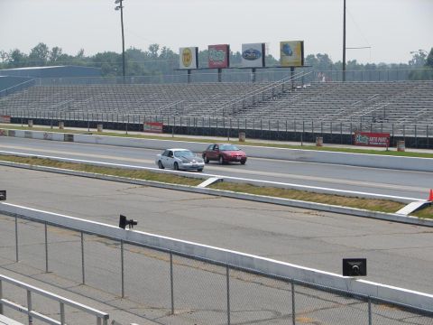 1992 Ford Taurus - Two cars compete on a drag racing track, with grandstands visible behind them.