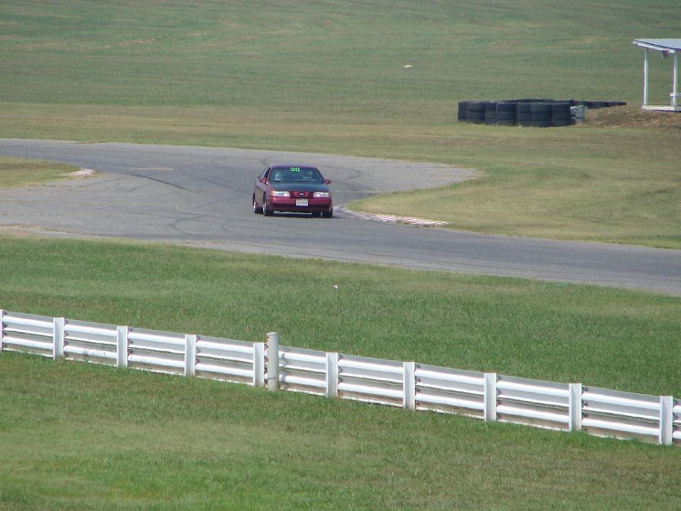 Red 1992 Ford Taurus sedan on a race track, front 3/4 view, with number 20 on windshield