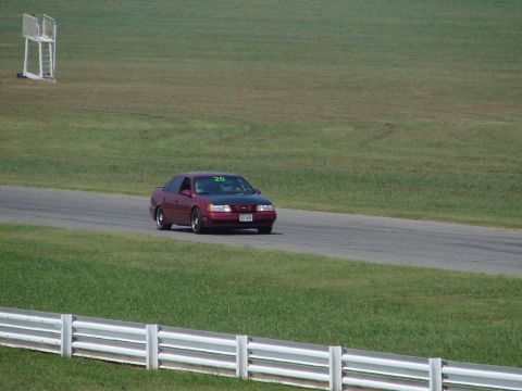 1992 Ford Taurus - A red 1992 Ford Taurus with a black hood races on a track, displaying the number 20 on its windshield.