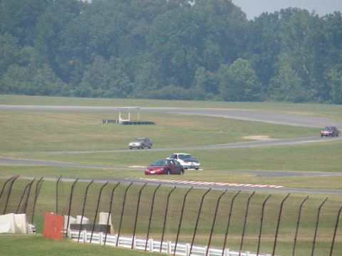 1992 Ford Taurus - Multiple vehicles are seen on a racetrack during a sunny day.
