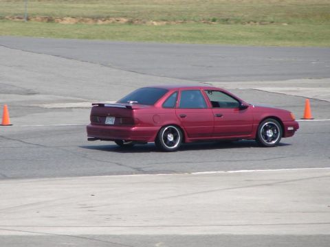 1992 Ford Taurus - This sedan is on a race track, navigating around an orange cone.