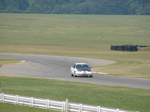 1992 Ford Taurus - A white 1992 Ford Taurus with a black hood navigates a turn on a racetrack.