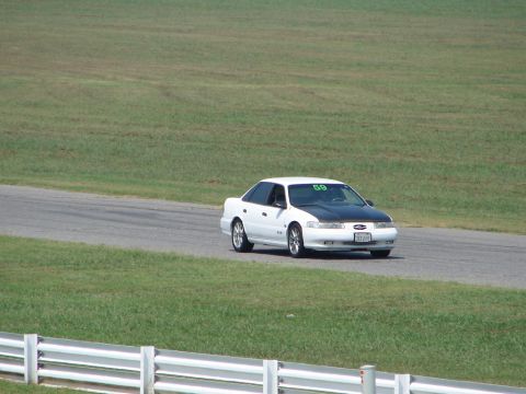 1992 Ford Taurus - White 1992 Ford Taurus with a black hood driving on a racetrack.