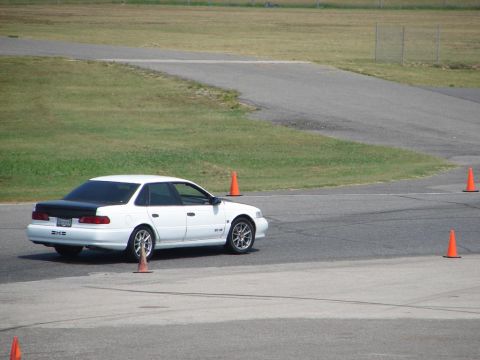 1992 Ford Taurus - A white 1992 Ford Taurus with a black trunk navigates a race track, marked by orange cones.