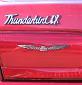 1995 Ford Thunderbird - A close-up view of the rear of a red vehicle, showing the 'Thunderbird' script and a winged emblem.