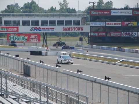 1992 Ford Taurus - A white sedan drives down a drag strip at Memphis Motorsports Park, with sponsor banners visible.