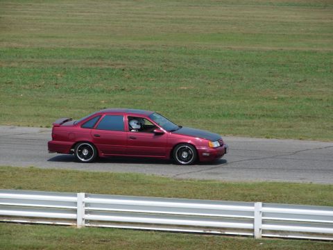 1992 Ford Taurus - This 1992 Ford Taurus is seen on a race track with a driver wearing a helmet.