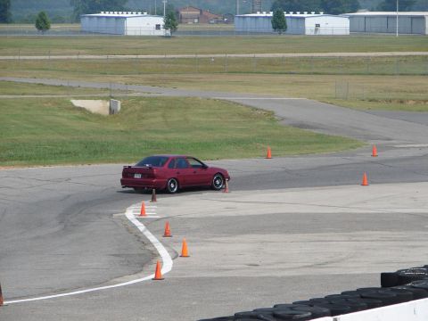 1992 Ford Taurus - A 1992 Ford Taurus navigates a turn on a race track, marked by orange cones.