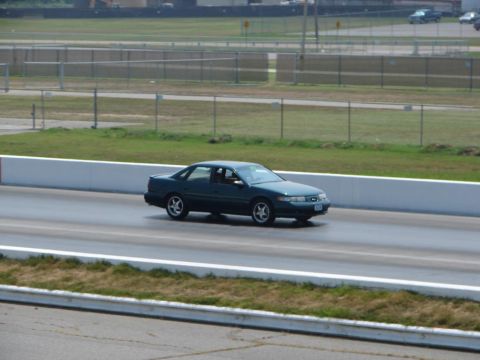 1992 Ford Taurus - A dark green 1992 Ford Taurus sedan is seen driving on a race track.