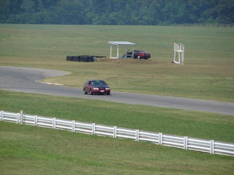 1992 Ford Taurus - Two cars on a race track, one in motion and one parked under a shelter.