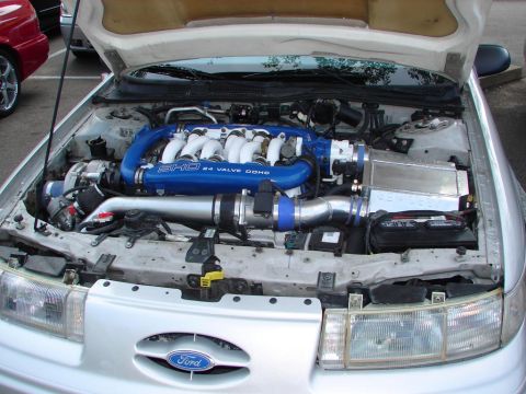 1992 Ford Taurus - The engine bay of a 1992 Ford Taurus SHO is shown with its hood open, highlighting the V8 engine and custom modifications.