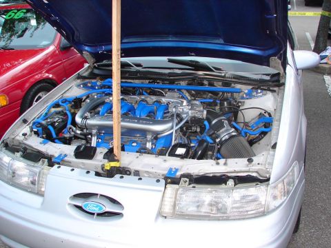 1992 Ford Taurus - The engine bay of a silver 1992 Ford Taurus is displayed with custom blue modifications.