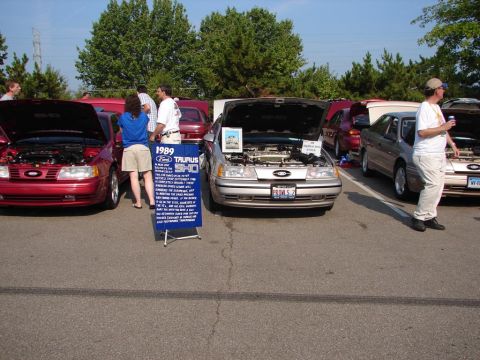 1992 Ford Taurus - A silver 1989 Ford Taurus SHO is displayed with its hood open at a car show, alongside other vehicles.