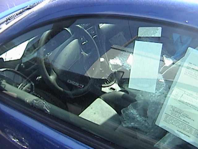 Blue car's black interior and steering wheel seen through the driver's window
