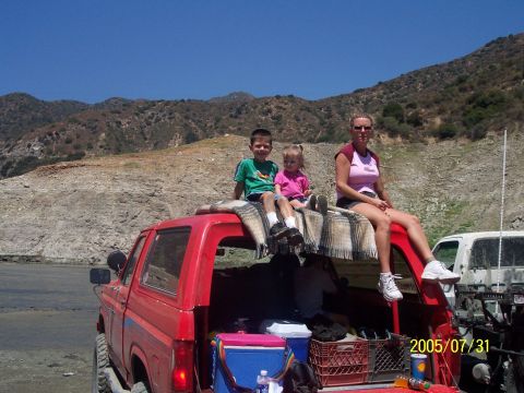 1985 Ford Bronco - A family enjoys a day out with their red SUV and a white vehicle in the background.