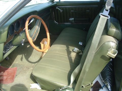 1975 Ford Torino - The interior of a vintage car shows green upholstery and a wood-grain dashboard.
