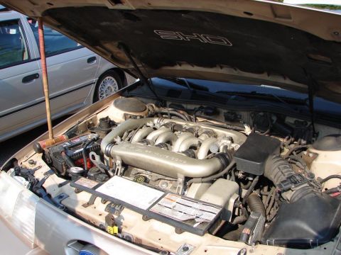 1992 Ford Taurus - The engine bay of a Ford SHO, identified by the hood liner badging, is shown with another vehicle in the background.