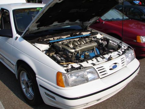 1992 Ford Taurus - 1992 Ford Taurus SHO engine bay detail, with a red car visible in the background.