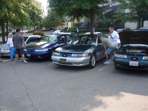 1992 Ford Taurus - Several Ford Taurus models are on display at an event, with one open for inspection.
