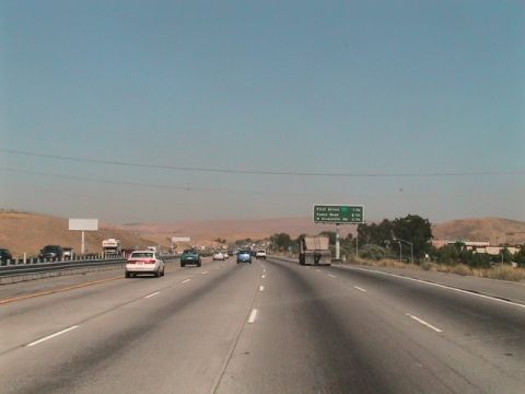 1971 Ford Bronco - Vehicles travel on a multi-lane highway under a clear sky, with a road sign indicating upcoming exits.