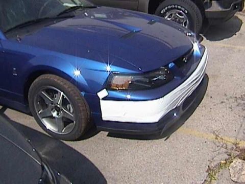 1989 Ford Mustang - Front view of a blue Ford Mustang, possibly a 2000 model, with a white protective cover on the bumper.