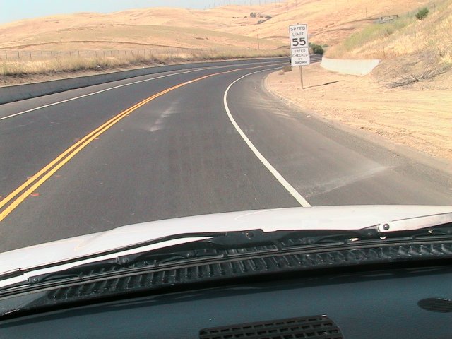 Dashboard view of a road with a 55 mph speed limit sign