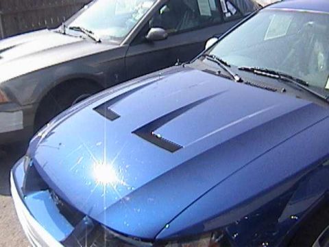 1989 Ford Mustang - A blue Ford Mustang with a distinctive hood design is parked next to another vehicle.