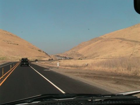1971 Ford Bronco - Driving on a highway through a dry, hilly landscape under a clear blue sky.