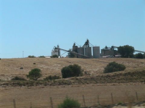 1971 Ford Bronco - A landscape view of large industrial grain silos situated on a dry, rolling hill.