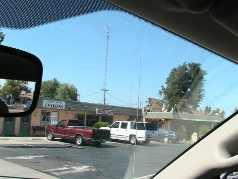 1971 Ford Bronco - A red pickup truck is parked next to a white SUV and a dark sedan in front of a strip mall.