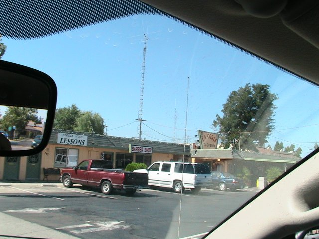 Red pickup truck parked in front of a building with a barber shop sign