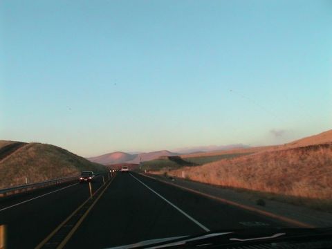 1971 Ford Bronco - Cars travel down a highway through rolling hills under a clear blue sky at dusk.
