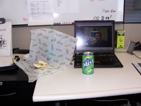 1971 Ford Bronco - A cluttered desk holds a sandwich, a soda, and a laptop showing a person on a video call.