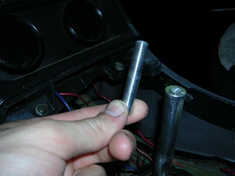 1996 Ford Probe - A hand holds a metal pin, likely for a shifter, near the car's interior console and wiring.