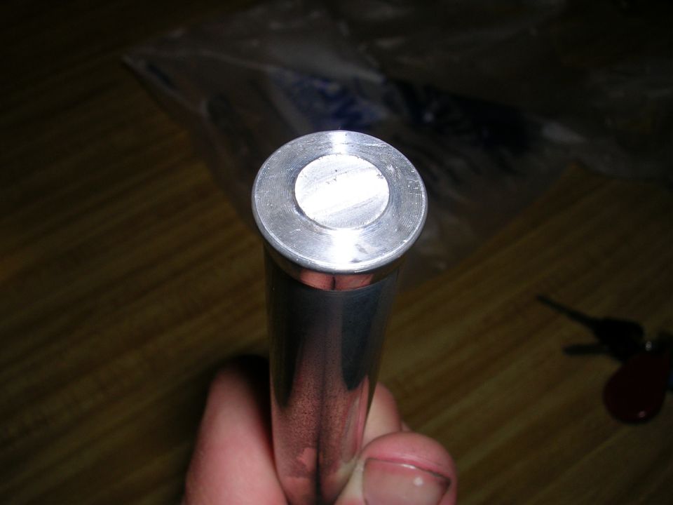 Hand holding a polished cylindrical machined metal part