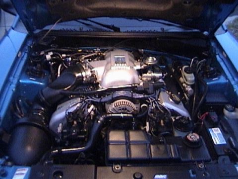 1989 Ford Mustang - The engine bay of a blue vehicle, a V8 engine and various components.